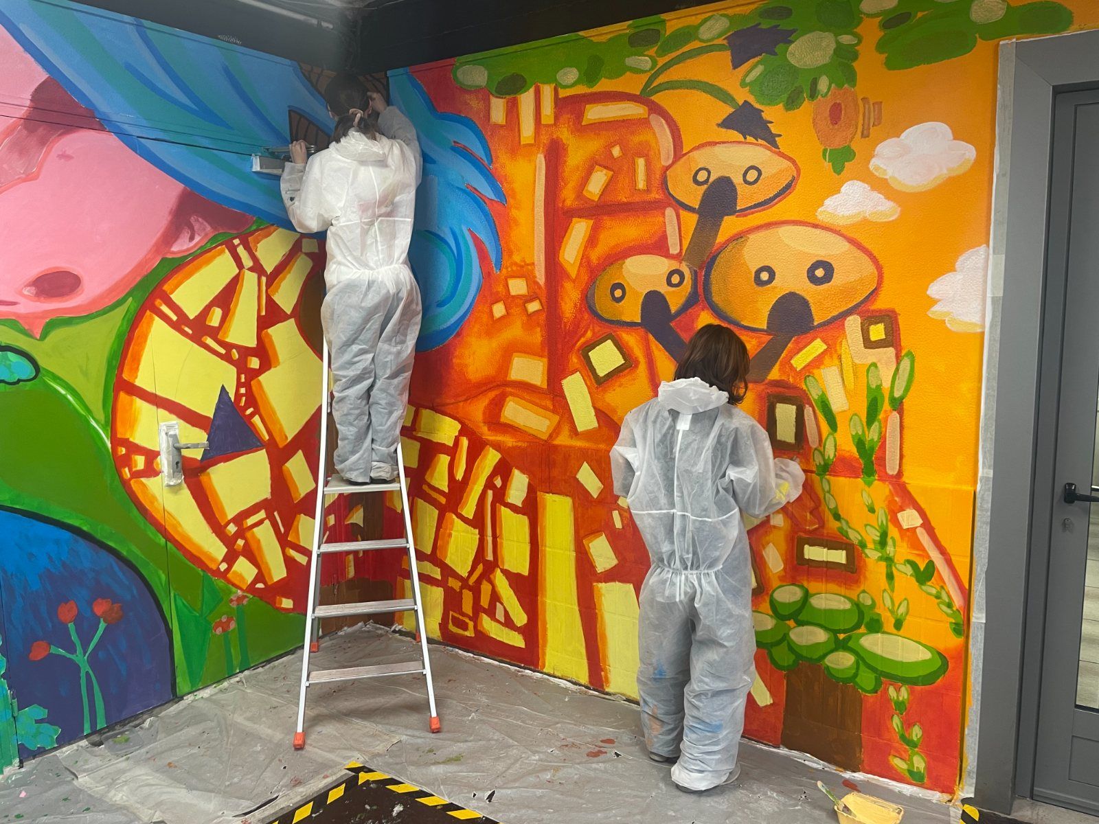 Deux élèves de l'option Arts plastiques peignant une fresque murale colorée au lycée Saint Thomas d'Aquin